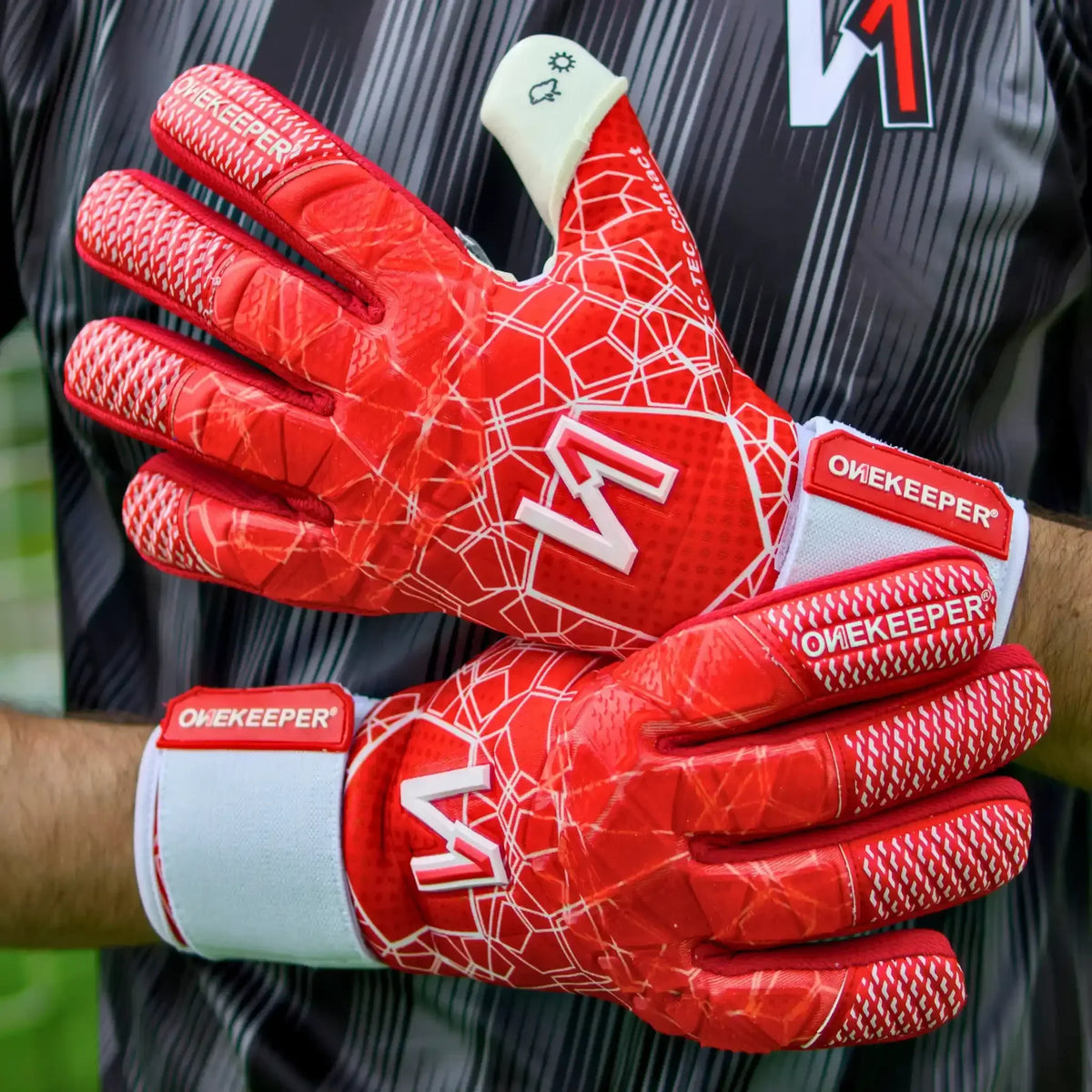 Red youth goalkeeper gloves with white geometric grip pattern and ONEKEEPER branding, designed for durable performance.