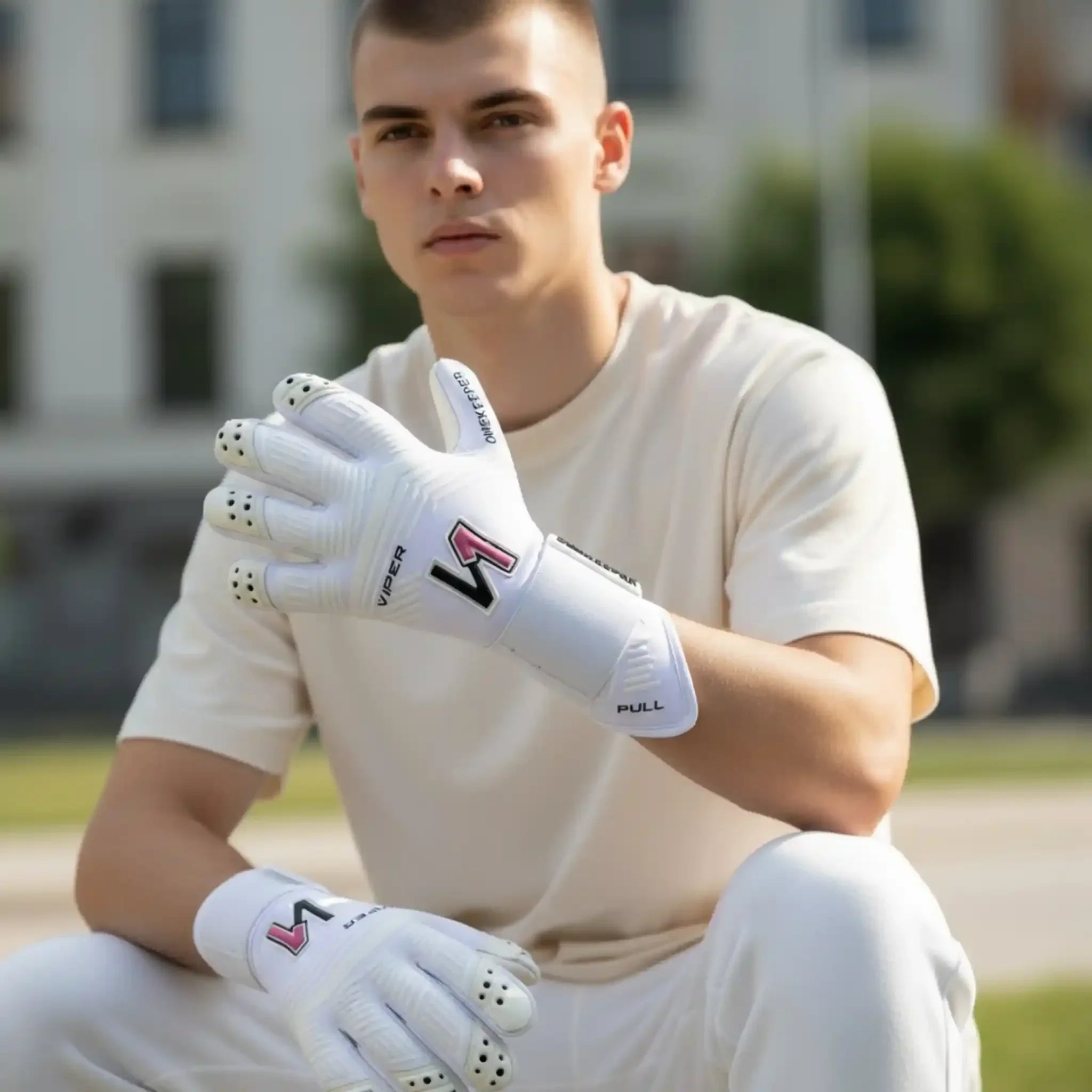 Youth goalkeeper wearing white Viper gloves with pink logo, designed for durable grip and pro-level performance.