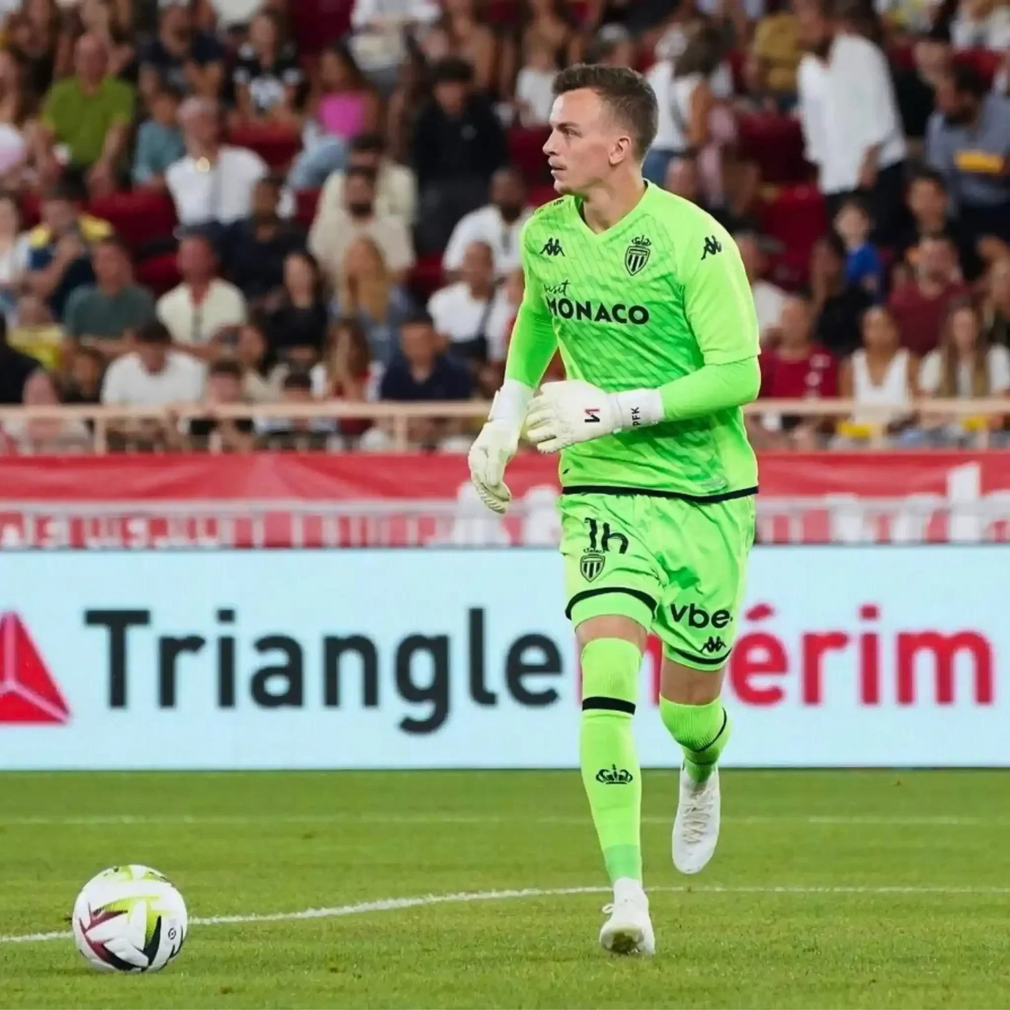 Soccer goalkeeper in neon green kit and white gloves on field during match