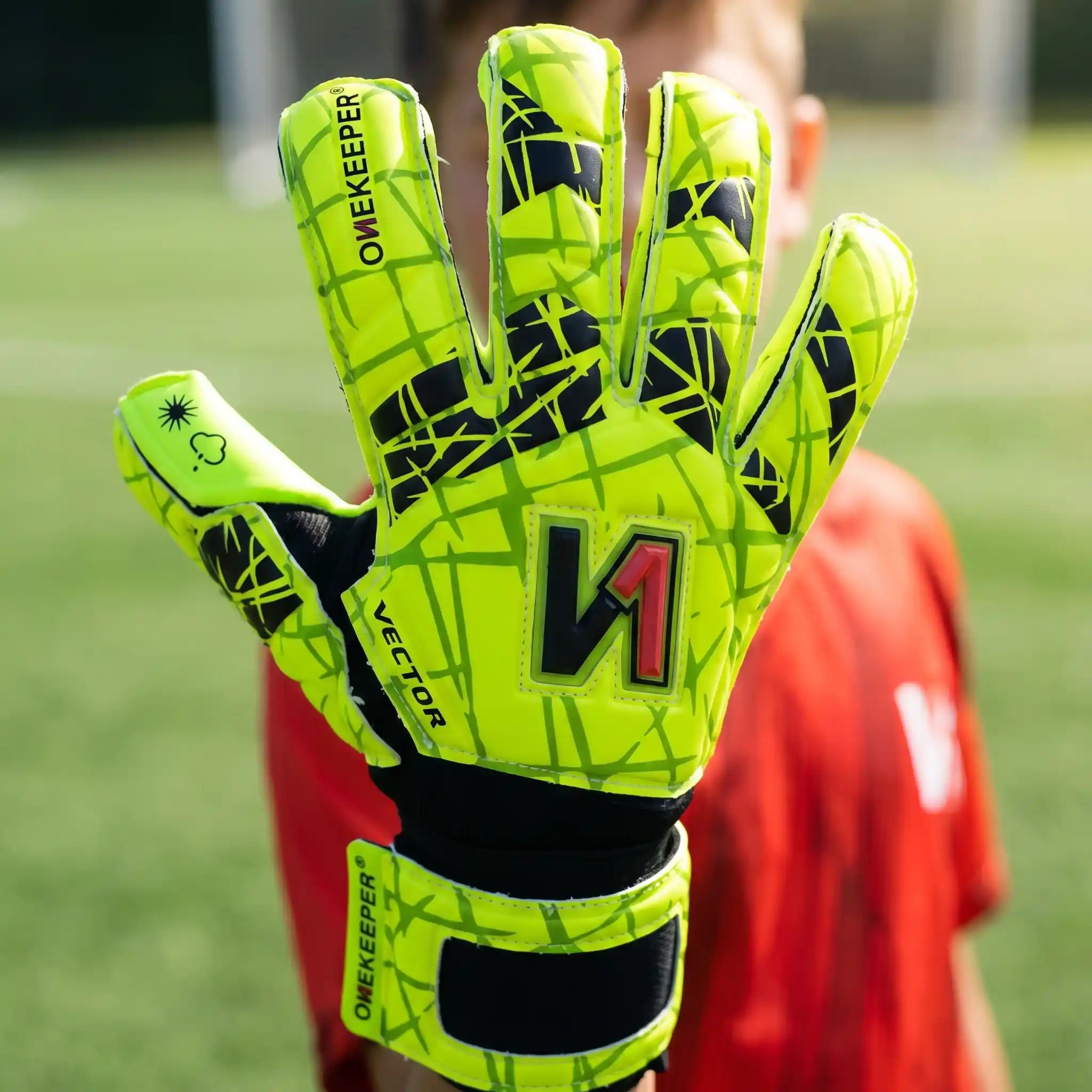 Bright neon green youth goalkeeper glove with black grip pattern, worn on soccer field