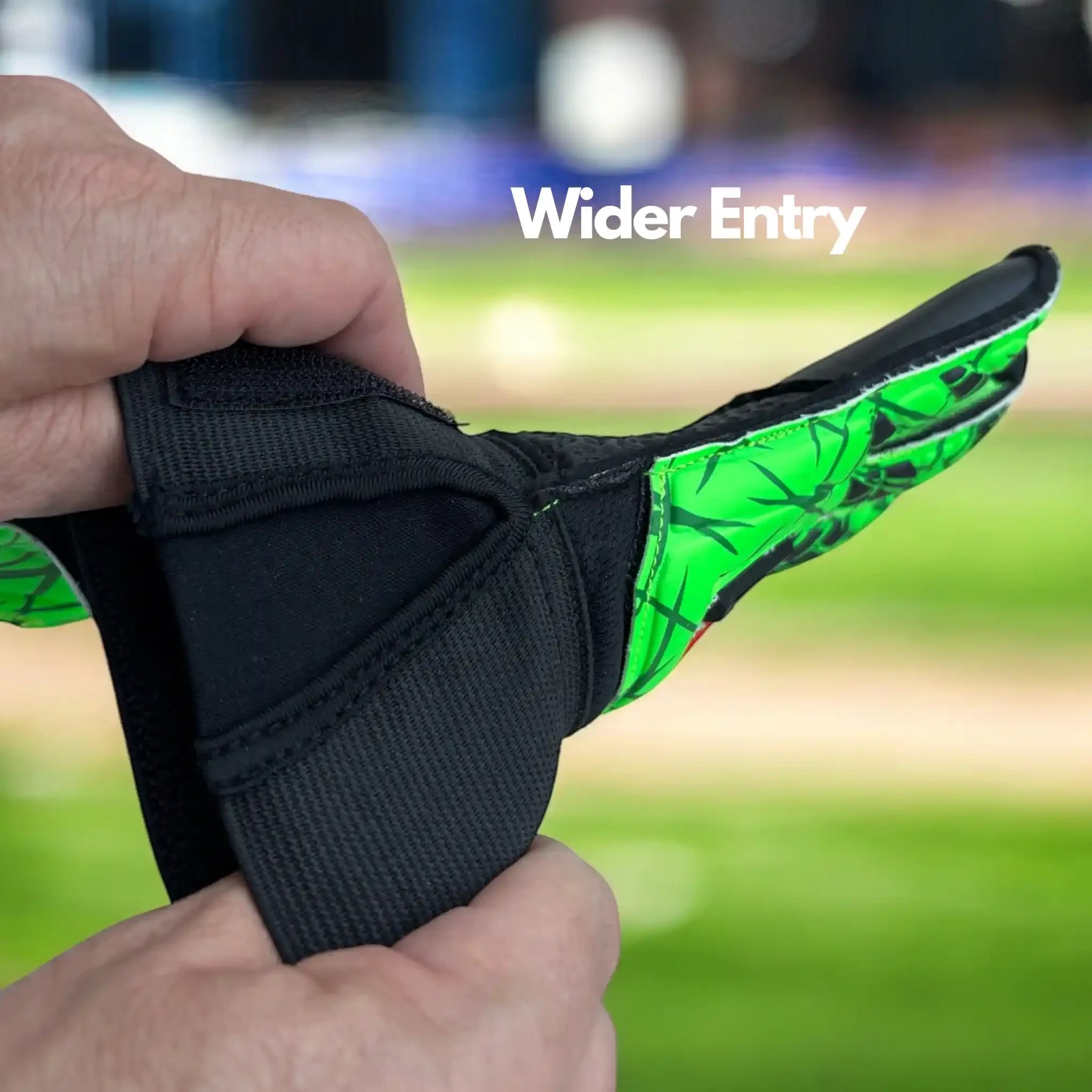 Hand holding ONEKEEPER USA premium goalkeeper glove with green design and wider entry feature