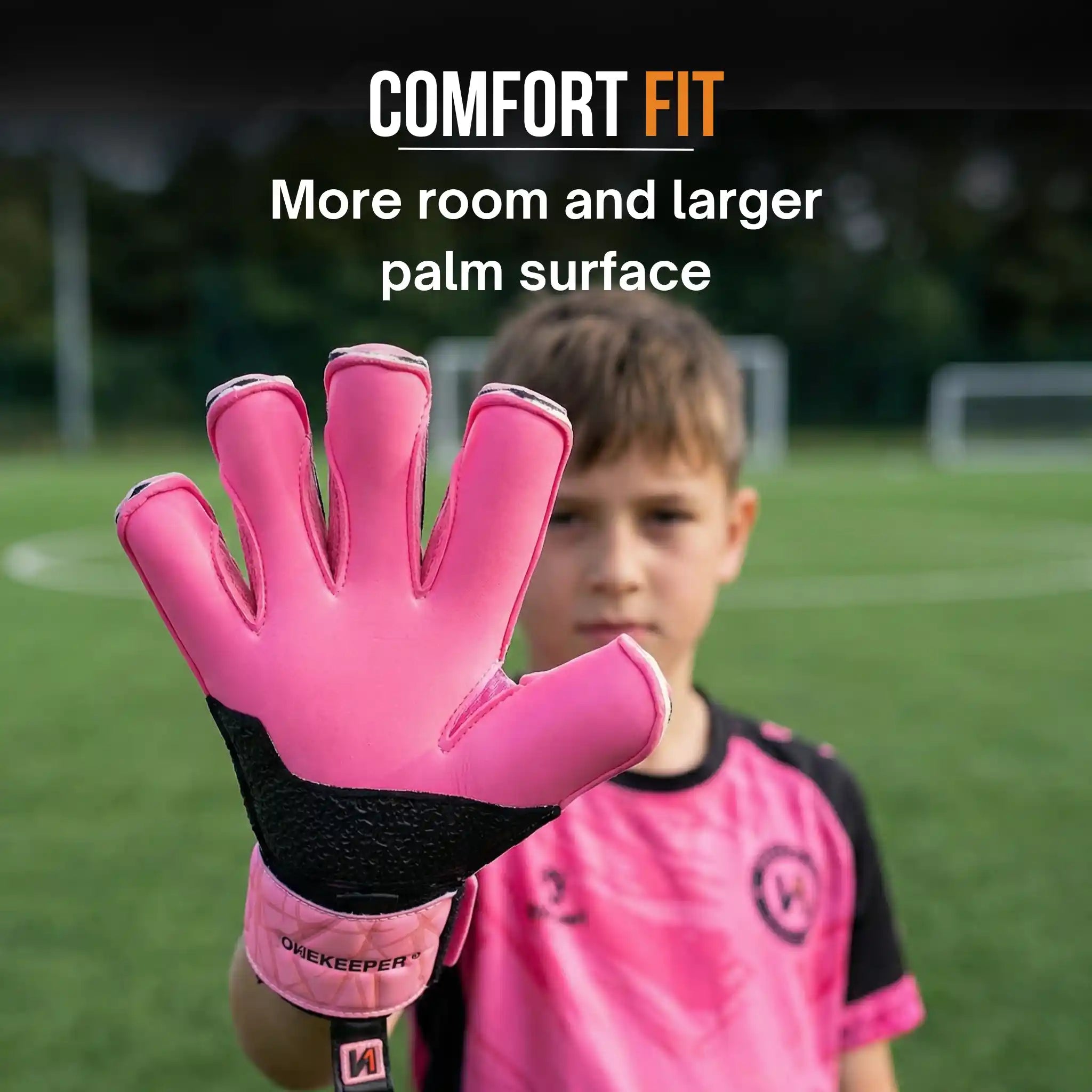 onekeeper vector evolution Pink goalkeeper glove with text 'Comfort Fit' on a blurred sports field background