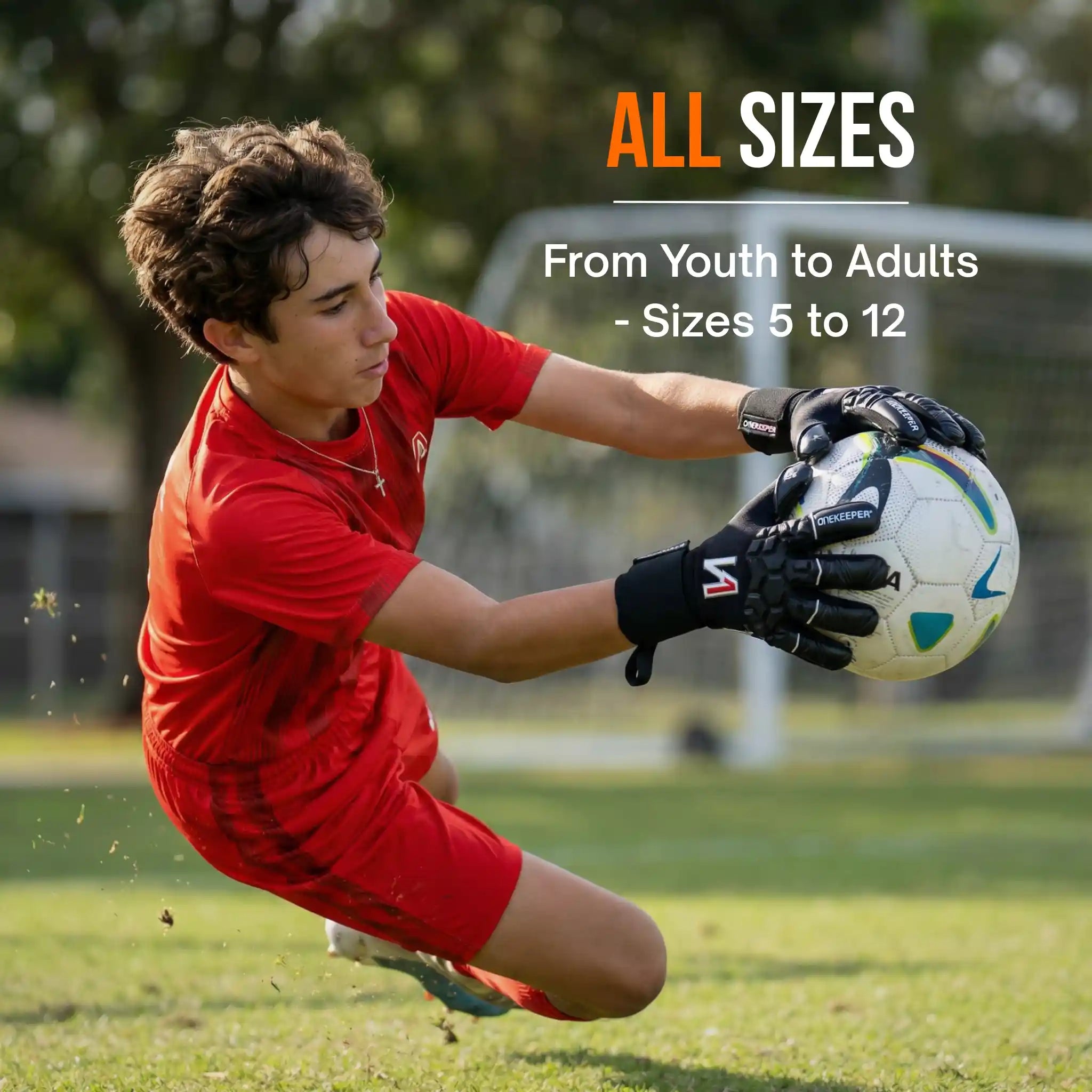 A young keeper in red soccer gear catching a ball on a field with text about size availability, using a onekeeper ace black goalie gloves.