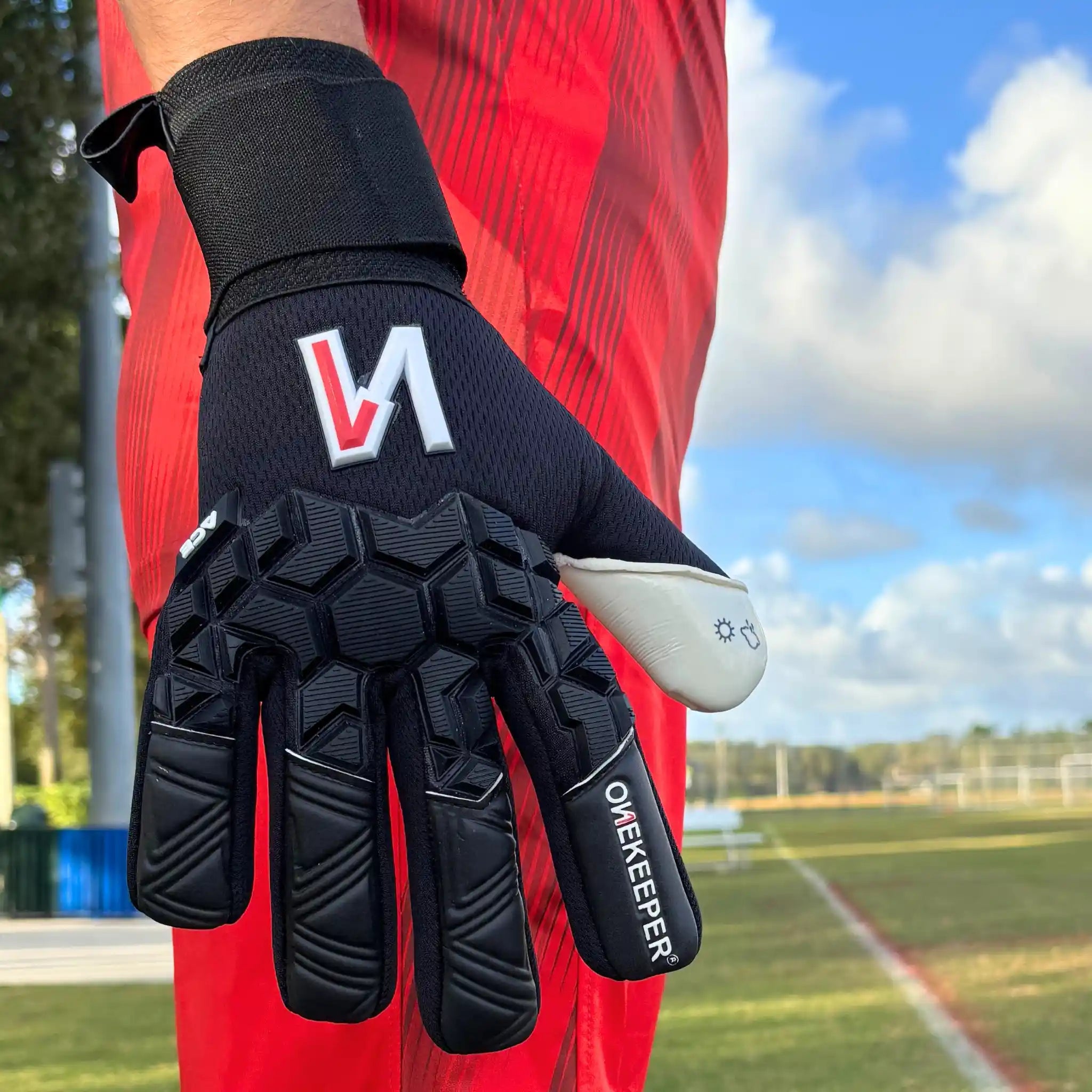 ONEKEEPER ACE Black and White goalkeeper glove with a logo on a soccer field