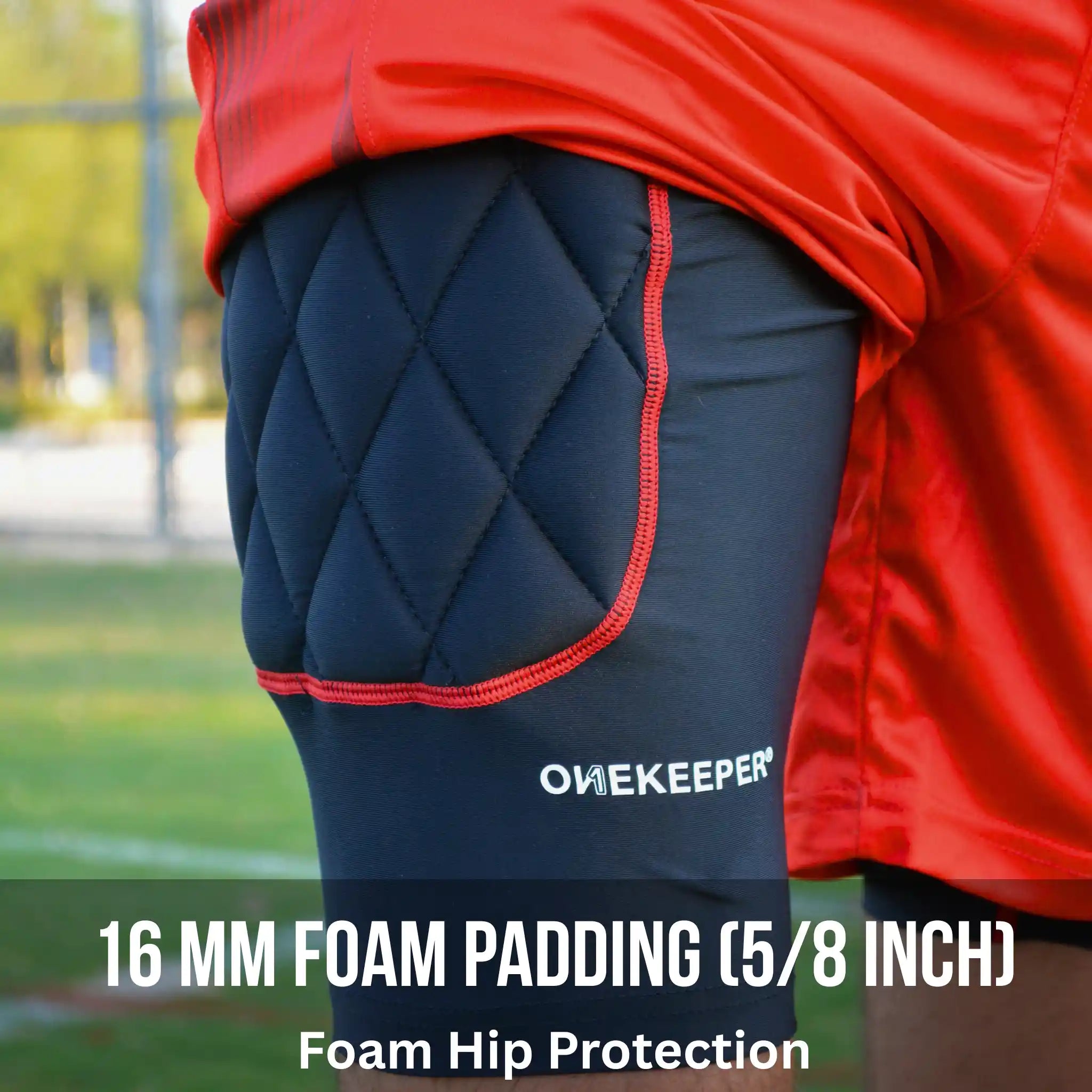 Compression-padded short foam hip protection with red accents worn by a person on a sports field, featuring 'ONEKEEPER' branding.
