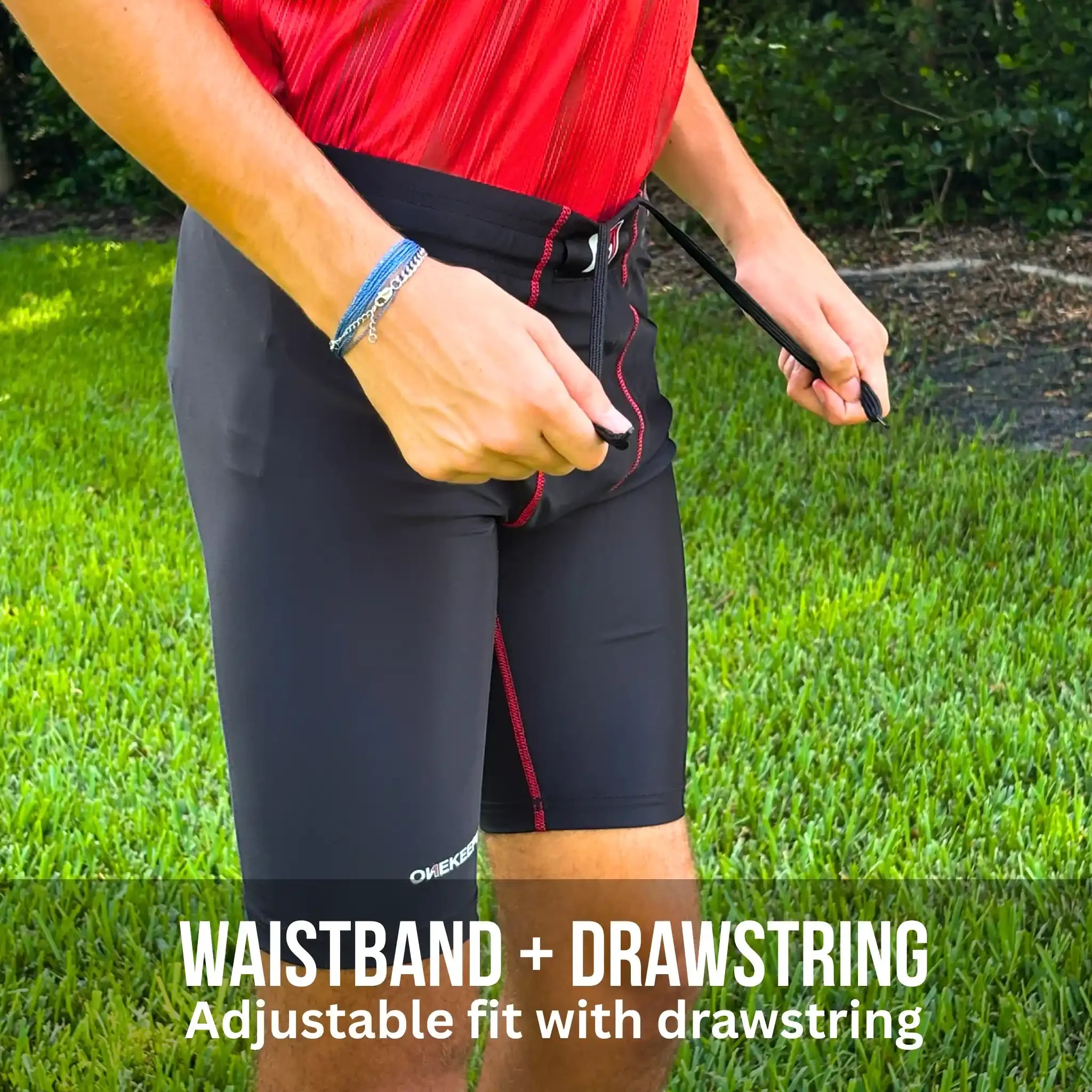 Person wearing black onekeeper compression shorts with waistband and drawstring feature on grass