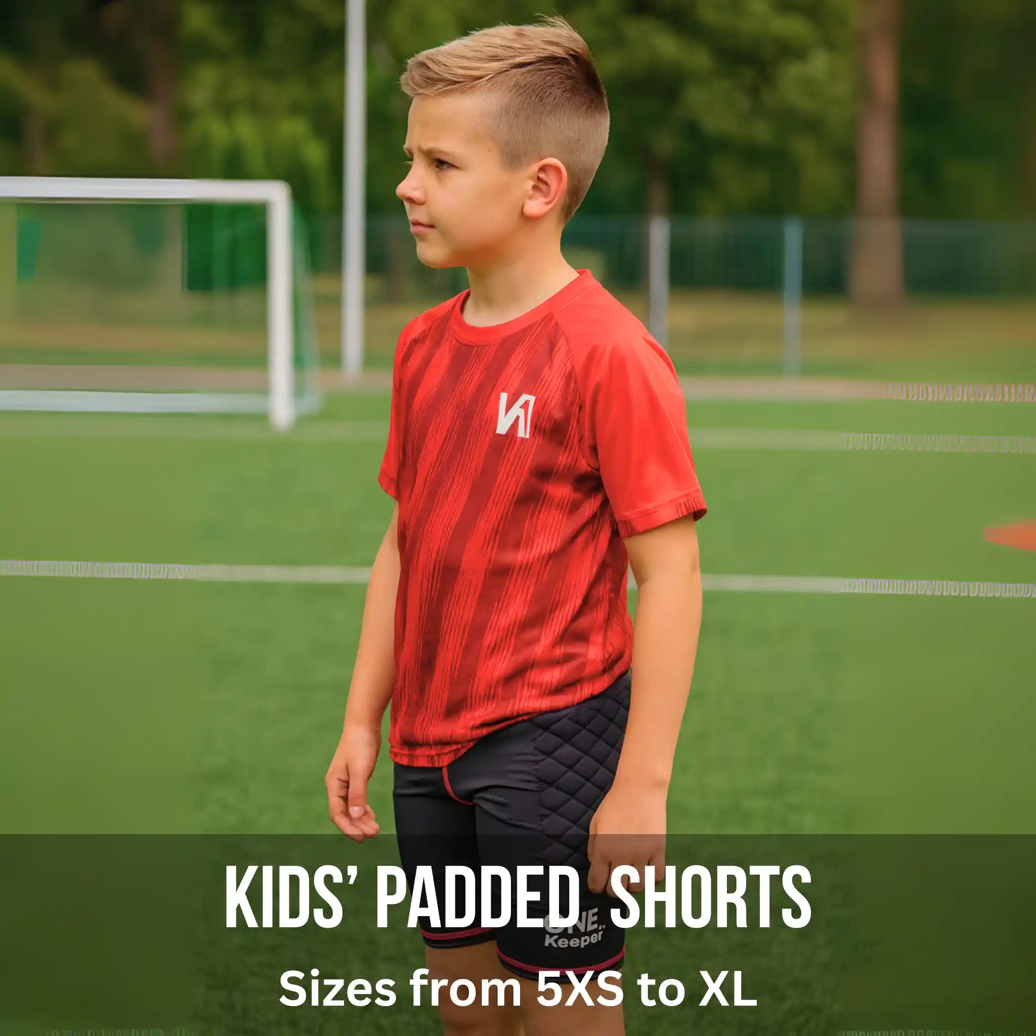 Child wearing red sports shirt and black compression-padded shorts on a soccer field