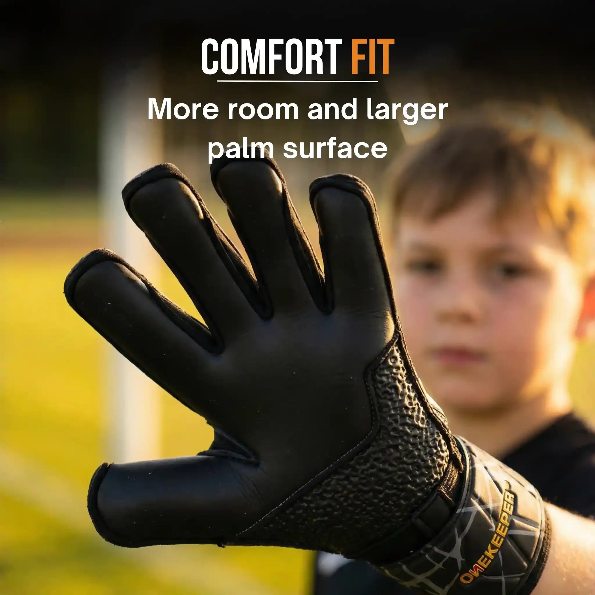 onekeeper vector evolution Black and gold glove with textured palm surface held by a person, with a blurred background of a child and grass.