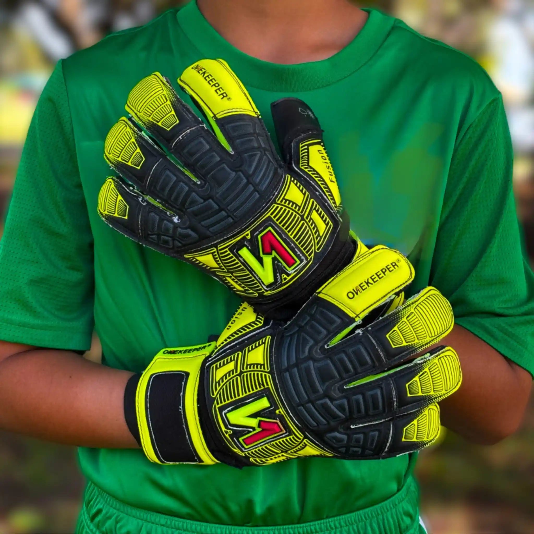 Person wearing green sports attire with onekeeper fusion yellow and black gloves on a blurred background
