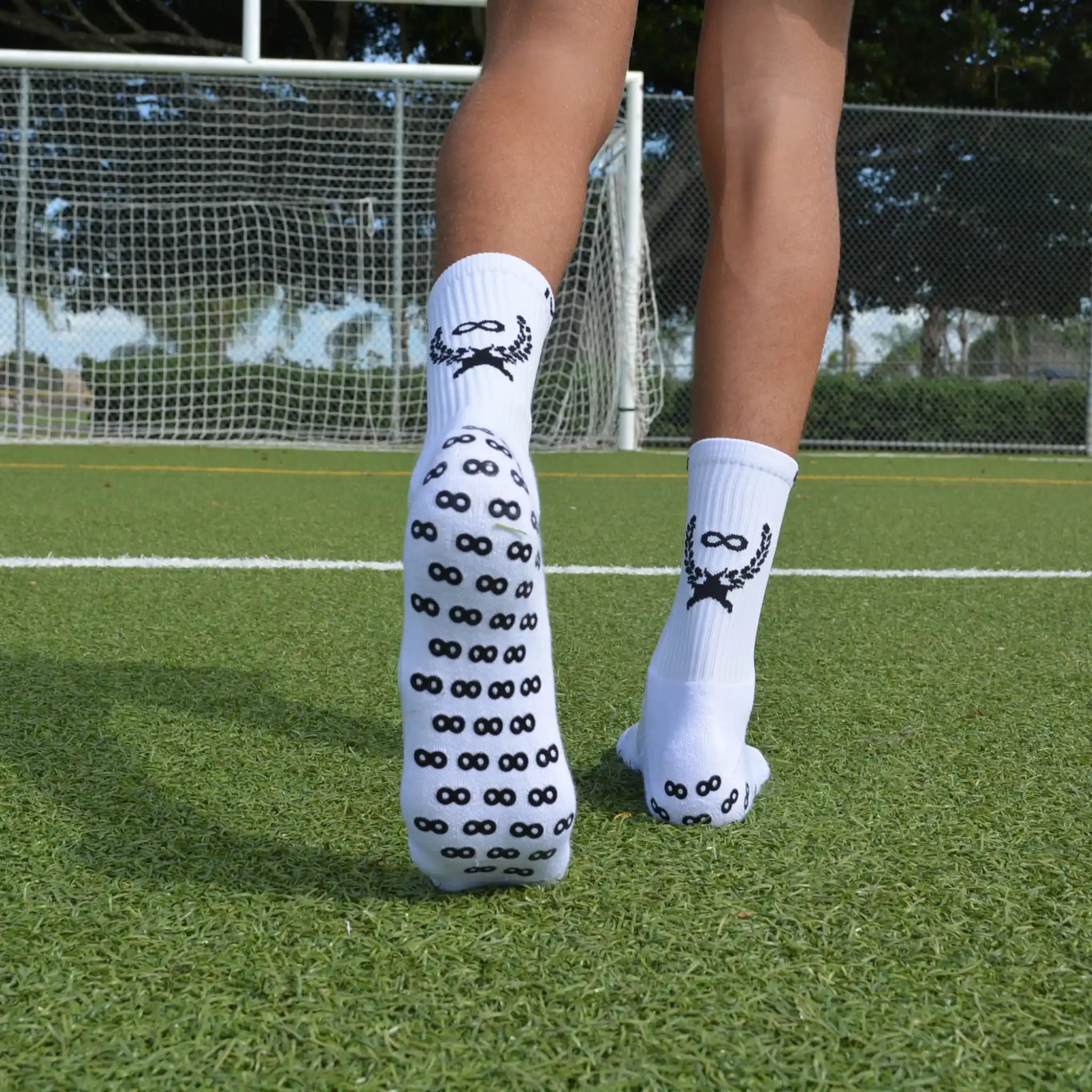 White grip socks with black patterns worn on a grassy field.