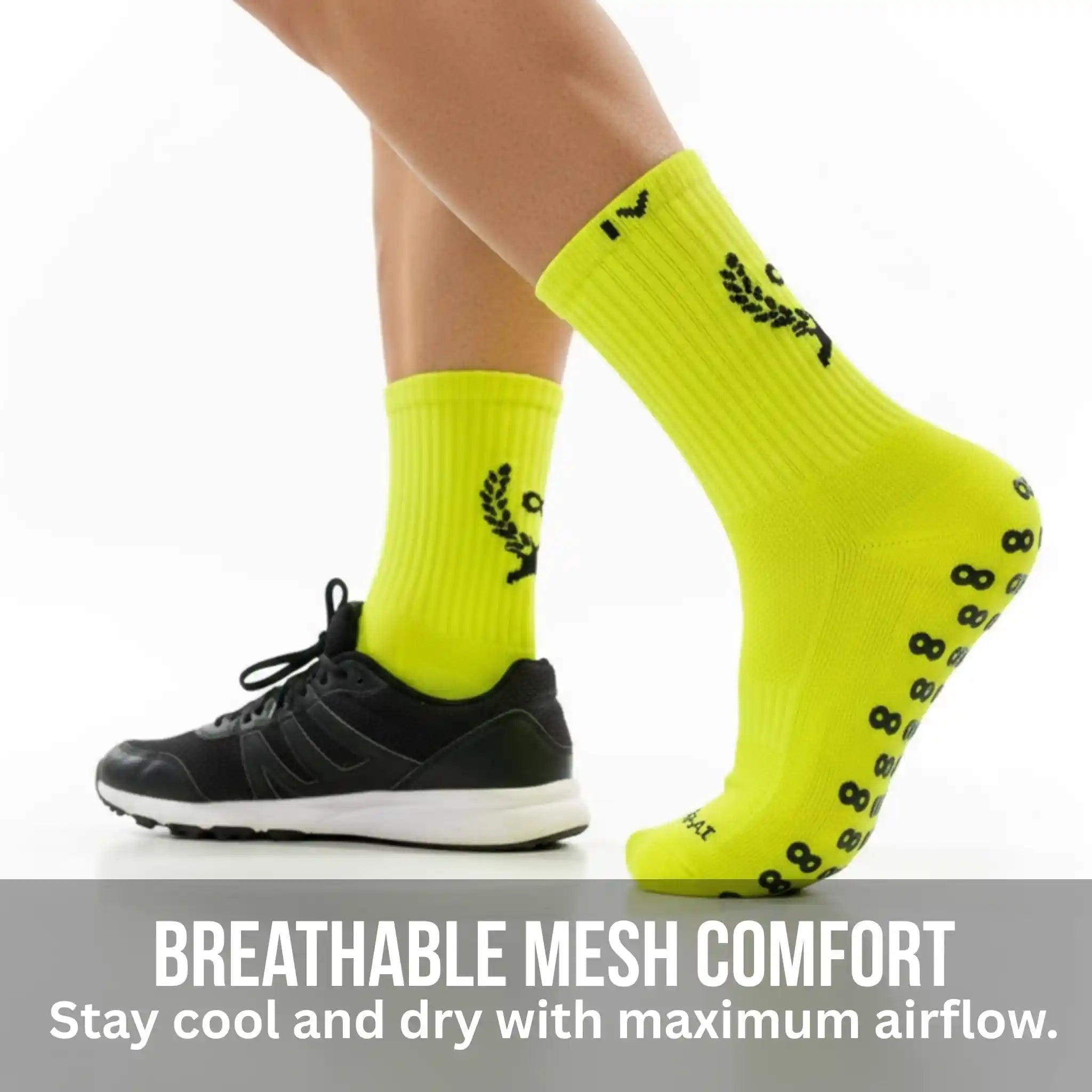 Neon yellow grip socks with black patterns worn by a person, on a white background.