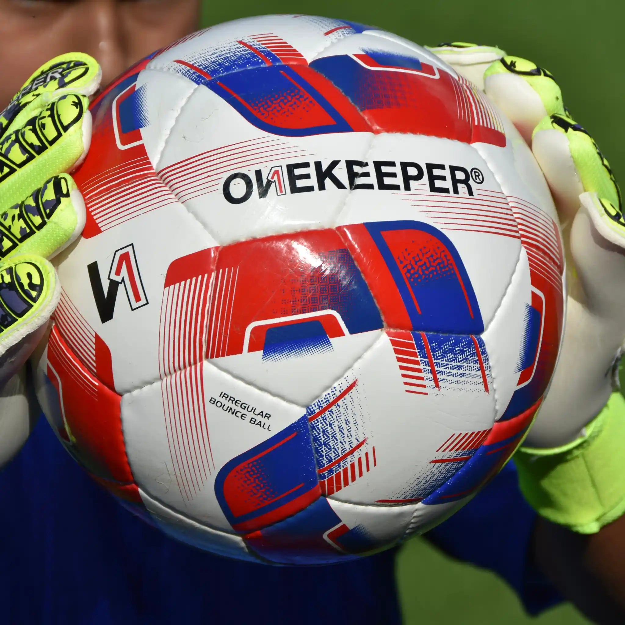 Close-up of a onekeeper irregular soccer ball with 'OneKeeper' branding held by goalkeeper gloves.