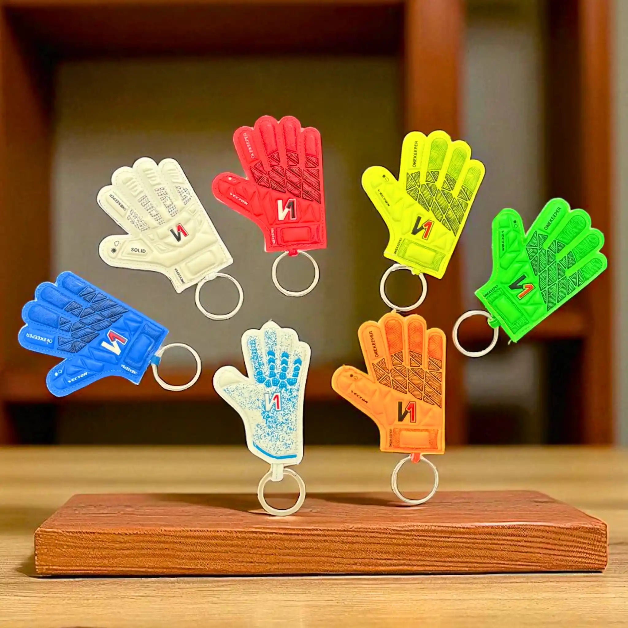Colorful ONEKEEPER glove-shaped keychains on a wooden stand with a blurred background