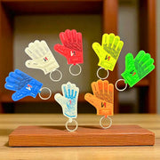 Colorful ONEKEEPER glove-shaped keychains on a wooden stand with a blurred background