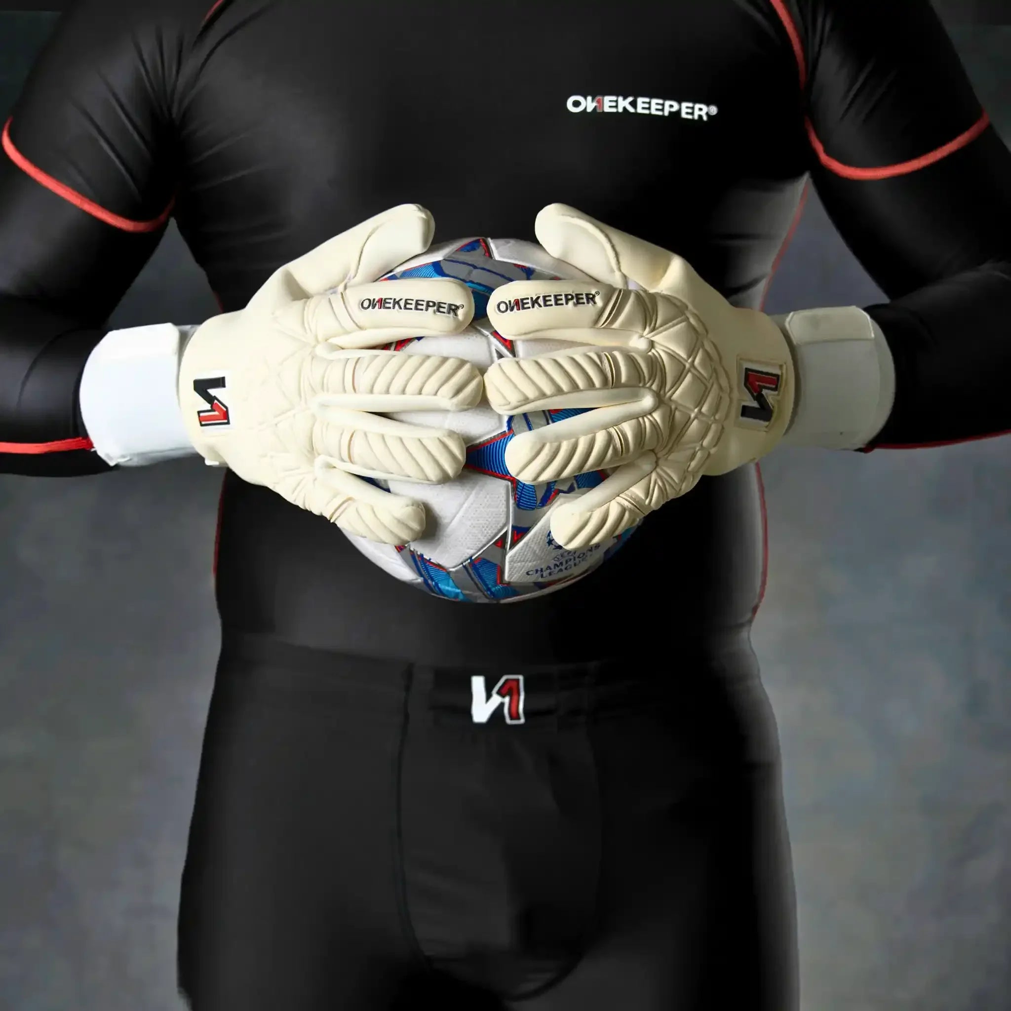 Goalkeeper wearing a onekeeper philipp kohn white gloves and black gear holding a soccer ball close to chest