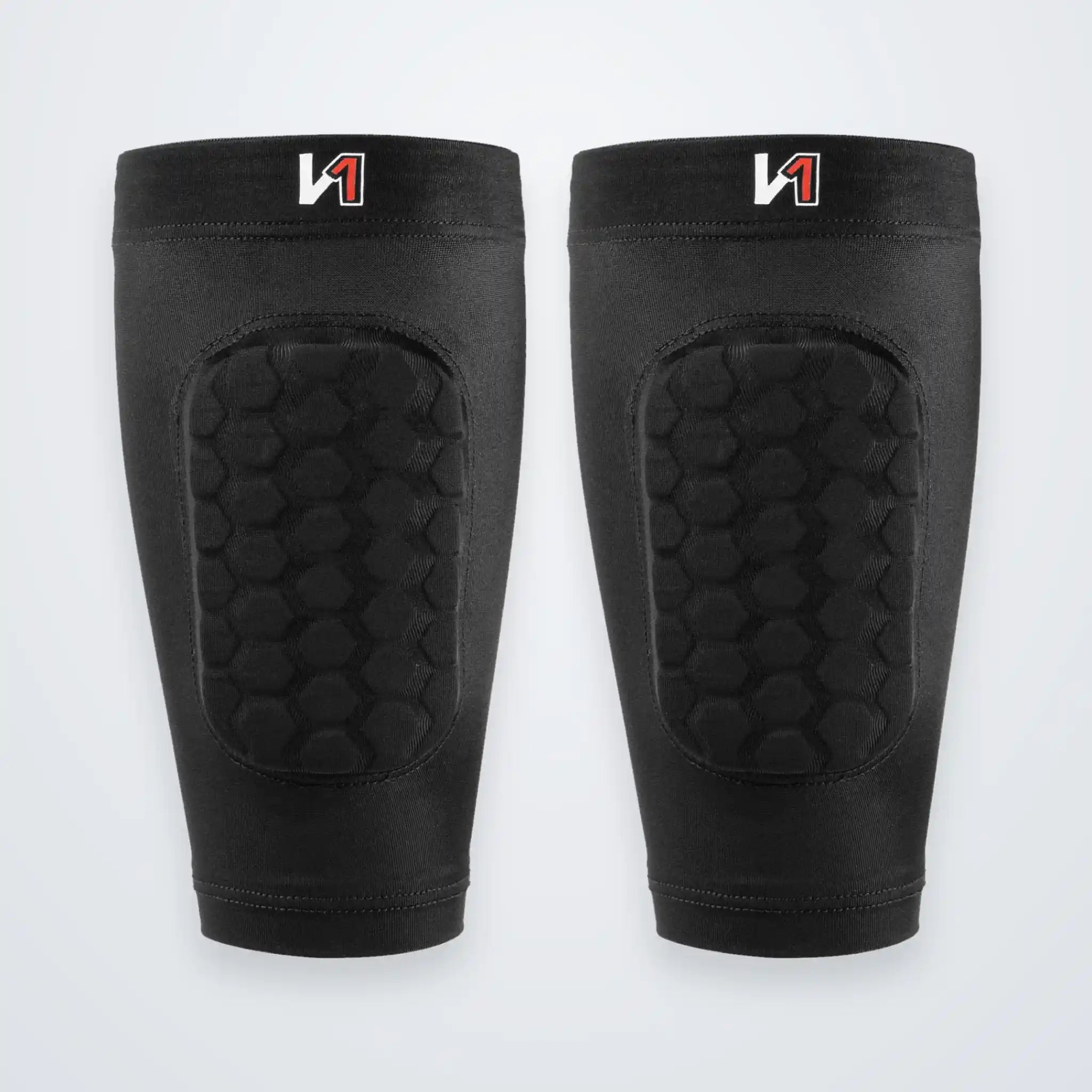 A pair of black protective shin guards with a honeycomb-patterned cushioned panel on the front, displayed side-by-side against a light gray background.