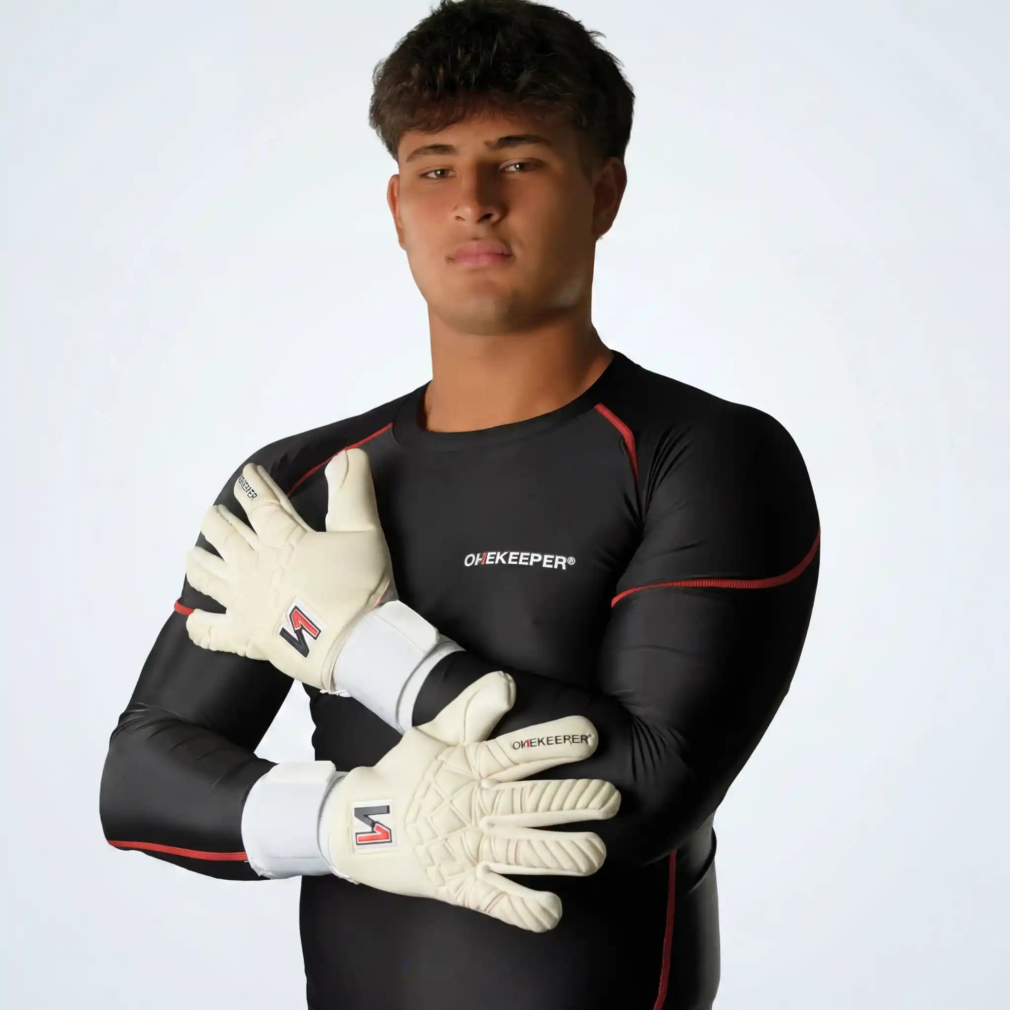 Person wearing a onekeeper black compression shirt long sleve sports outfit with white gloves on a plain background