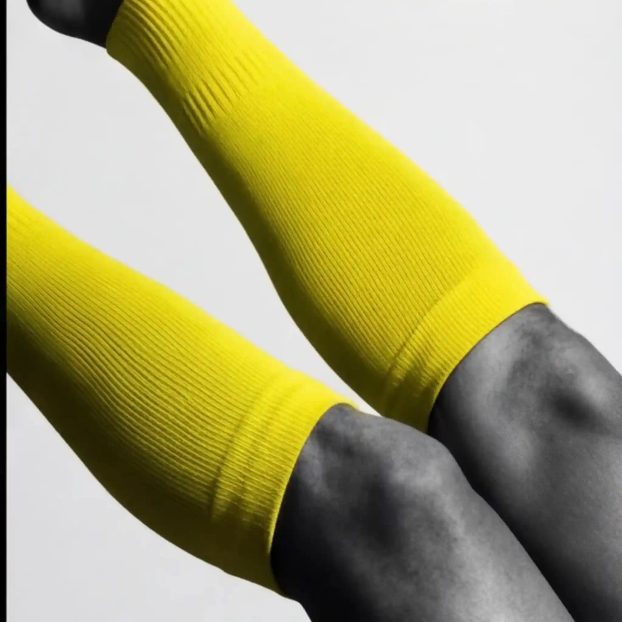 onekeeper Yellow compression sleeves on a person's arms against a gray background