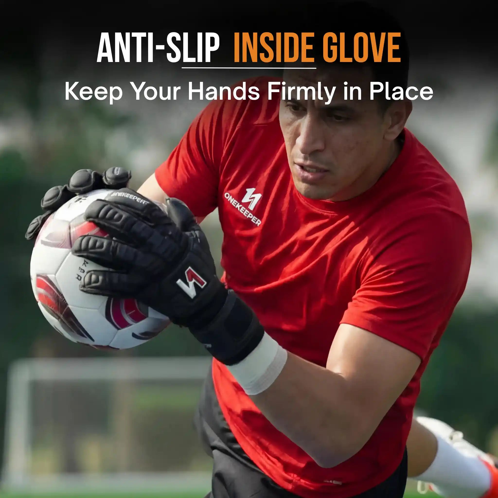 Person wearing a red shirt and onekeeper solid black gloves holding a soccer ball on a sports field.