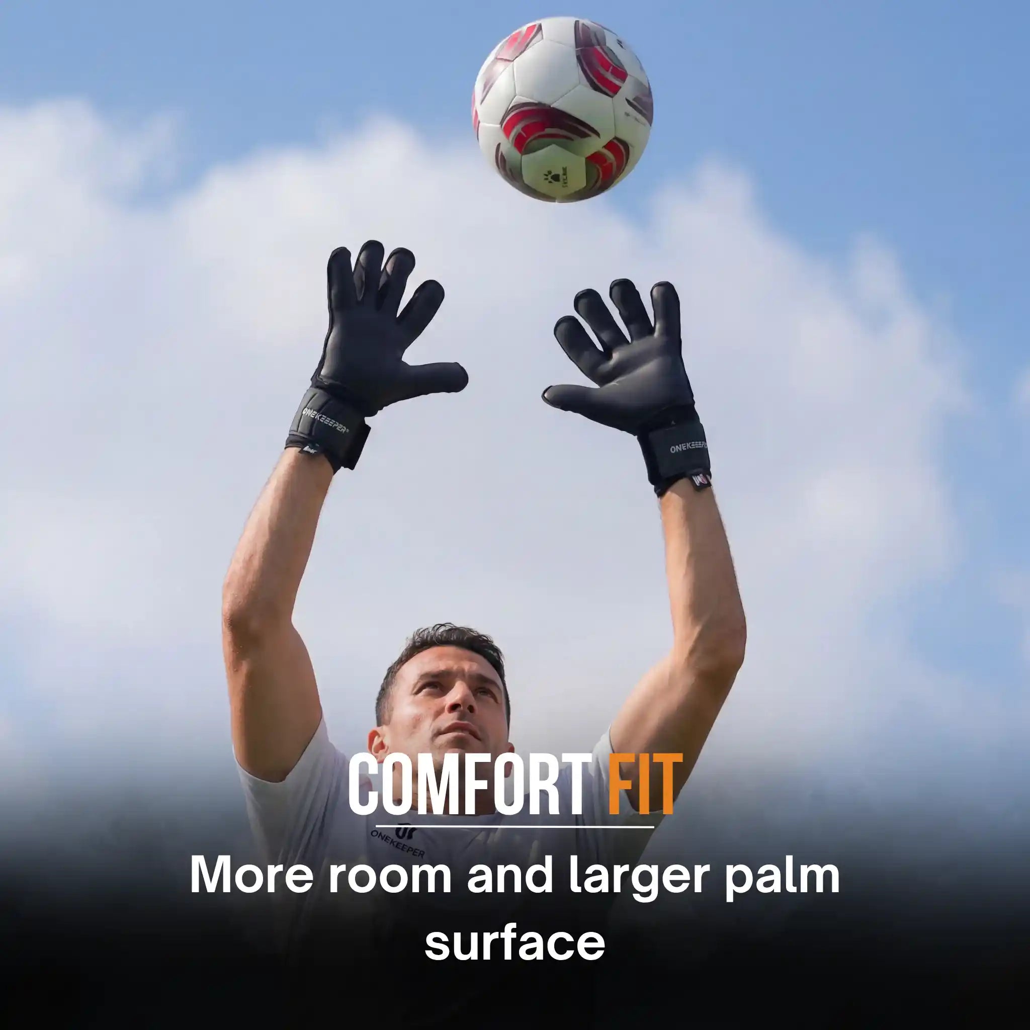 Person wearing a onekeeper solid black goalkeeper gloves catching a soccer ball with 'Comfort Fit' text overlay.