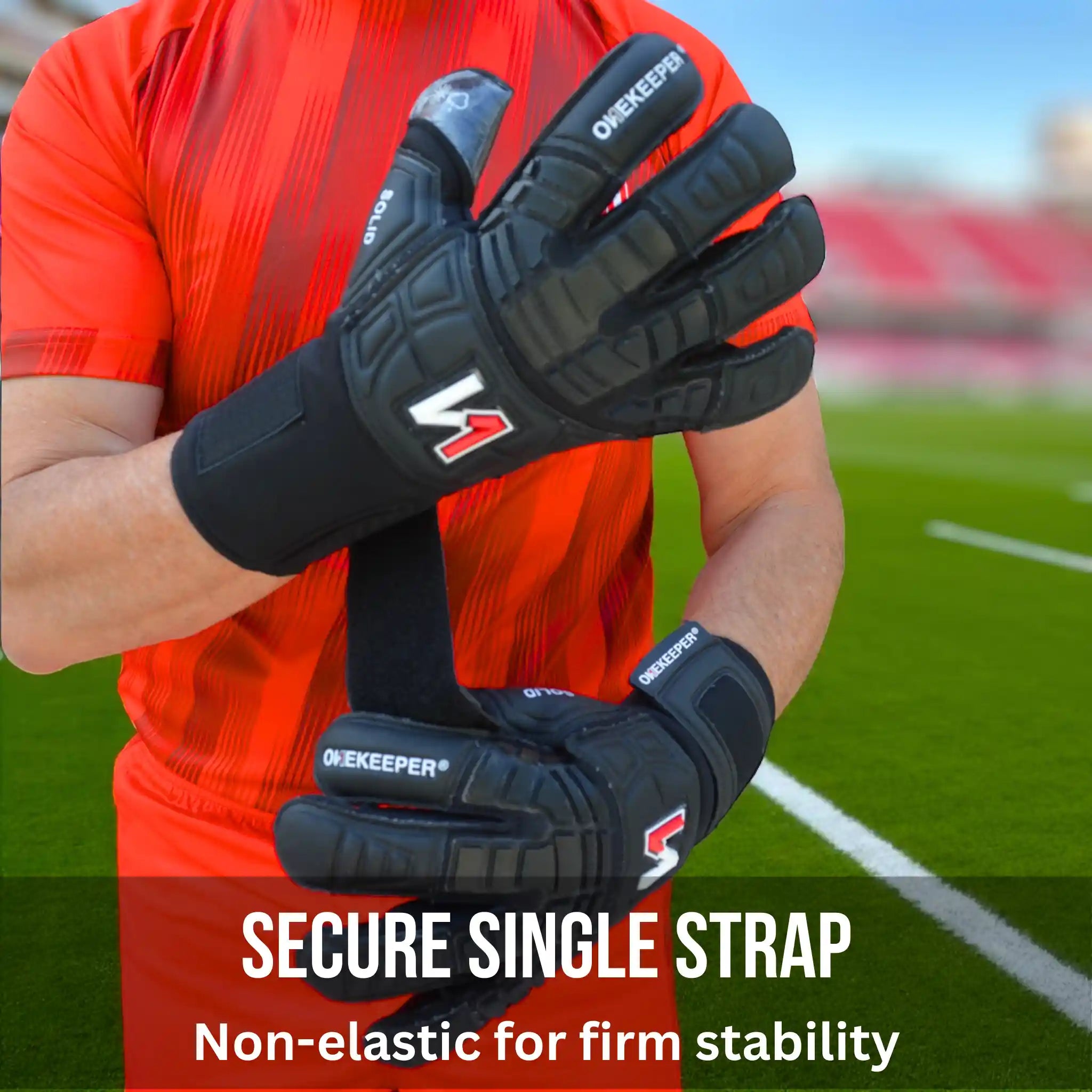 Person wearing a ONEKEEPER Solid black goalkeeper gloves with secure single strap on a sports field background