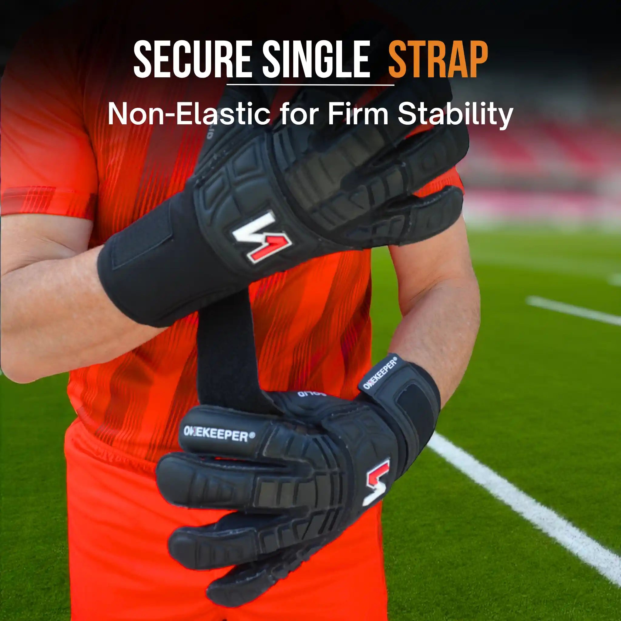 Person wearing a onekeeper solid black goalkeeper gloves with a secure single strap on a sports field background