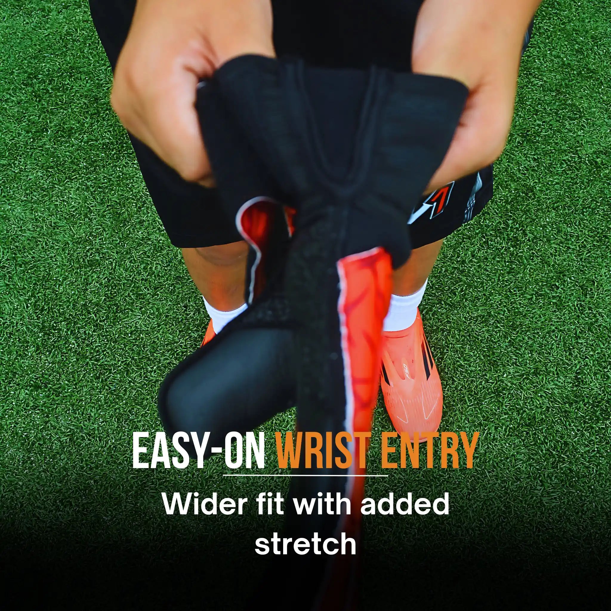 Person wearing a ONEKEEPER Vector Evolution Red black wrist guards with red accents on a grassy field, text 'EASY-ON WRIST ENTRY' and 'Wider fit with added stretch' displayed.