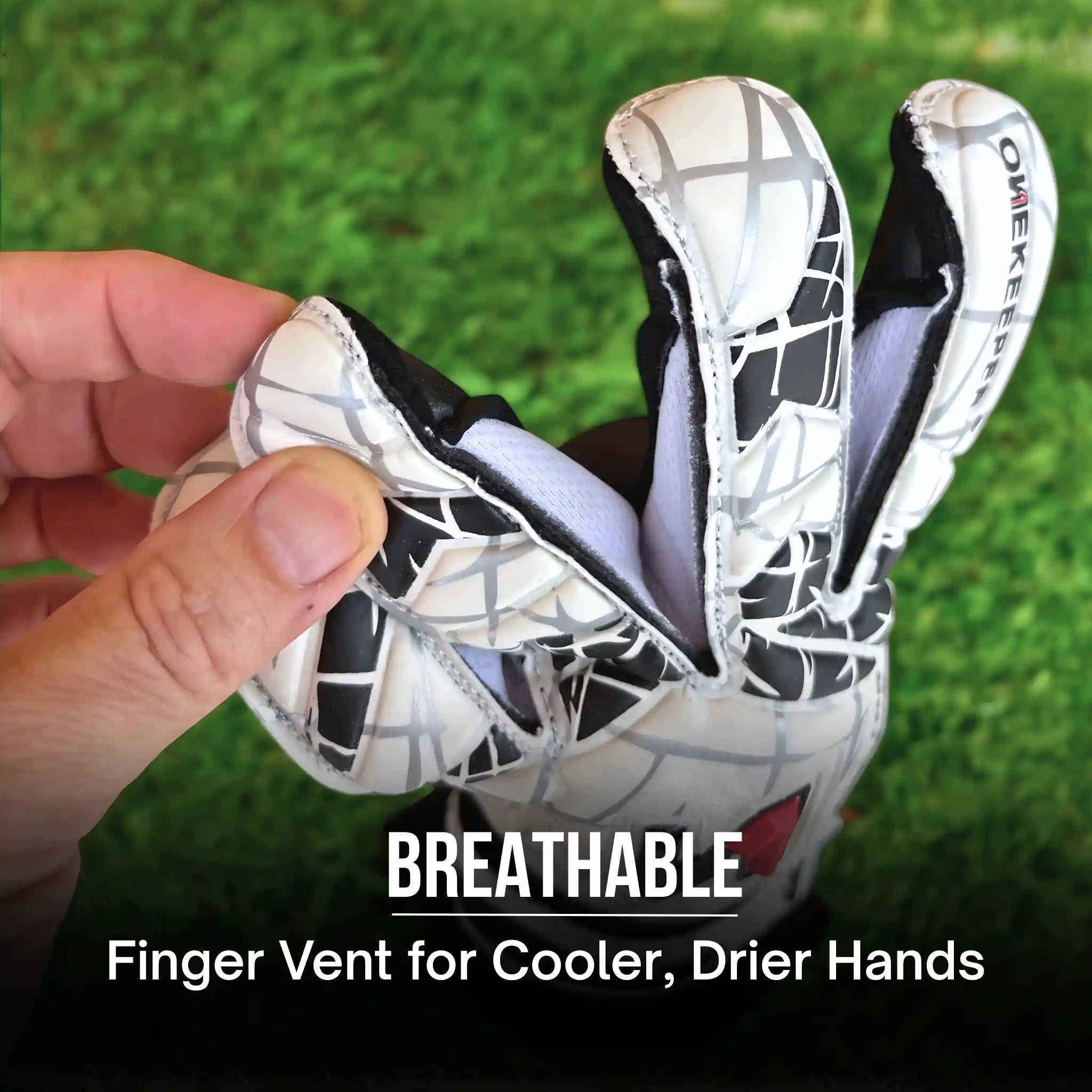 onekeeper vector evolution white and black Glove with breathable finger vent held by a hand on grass background