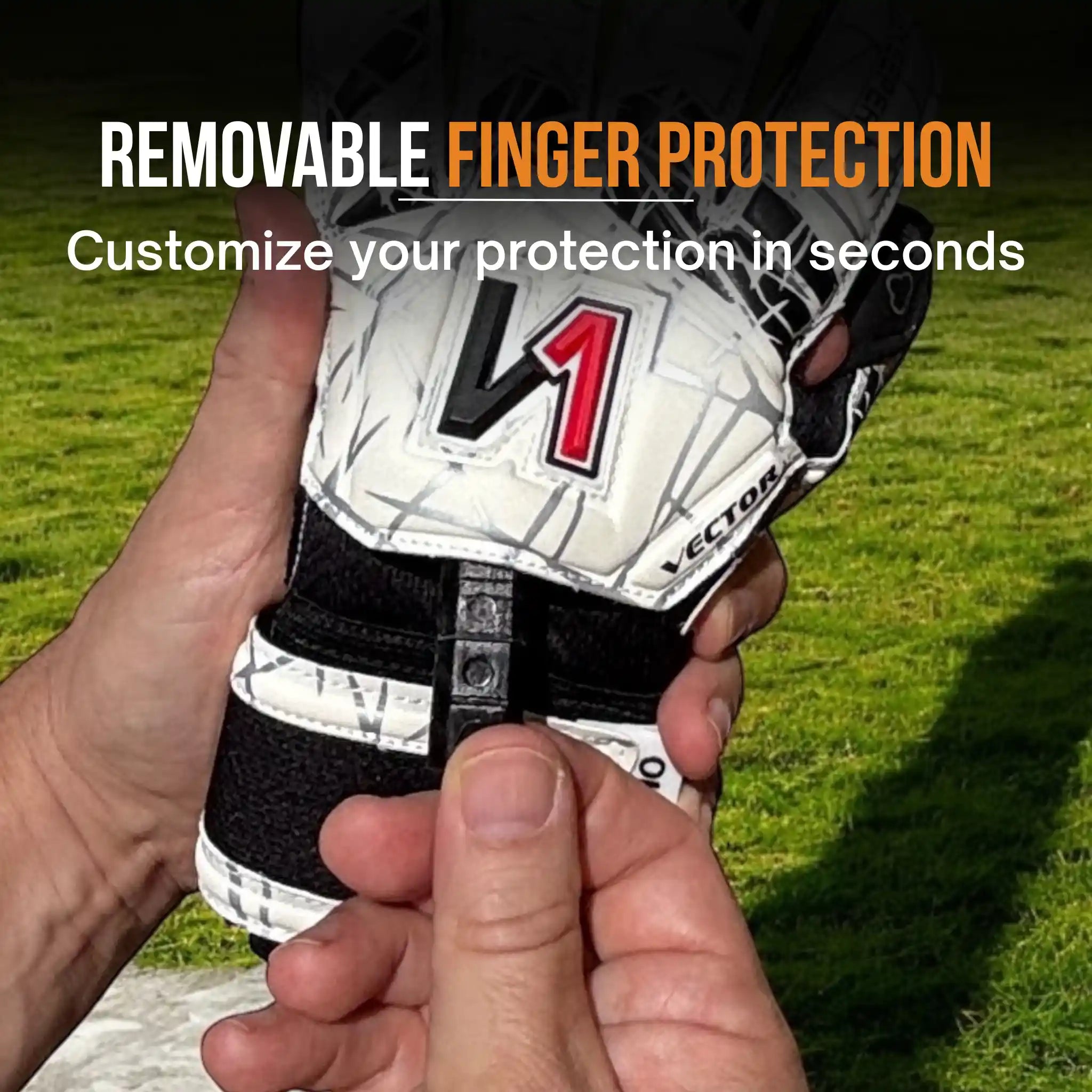 Hand holding a onekeeper vector evolution white and black goalkeeper glove with removable finger protection on a grassy background