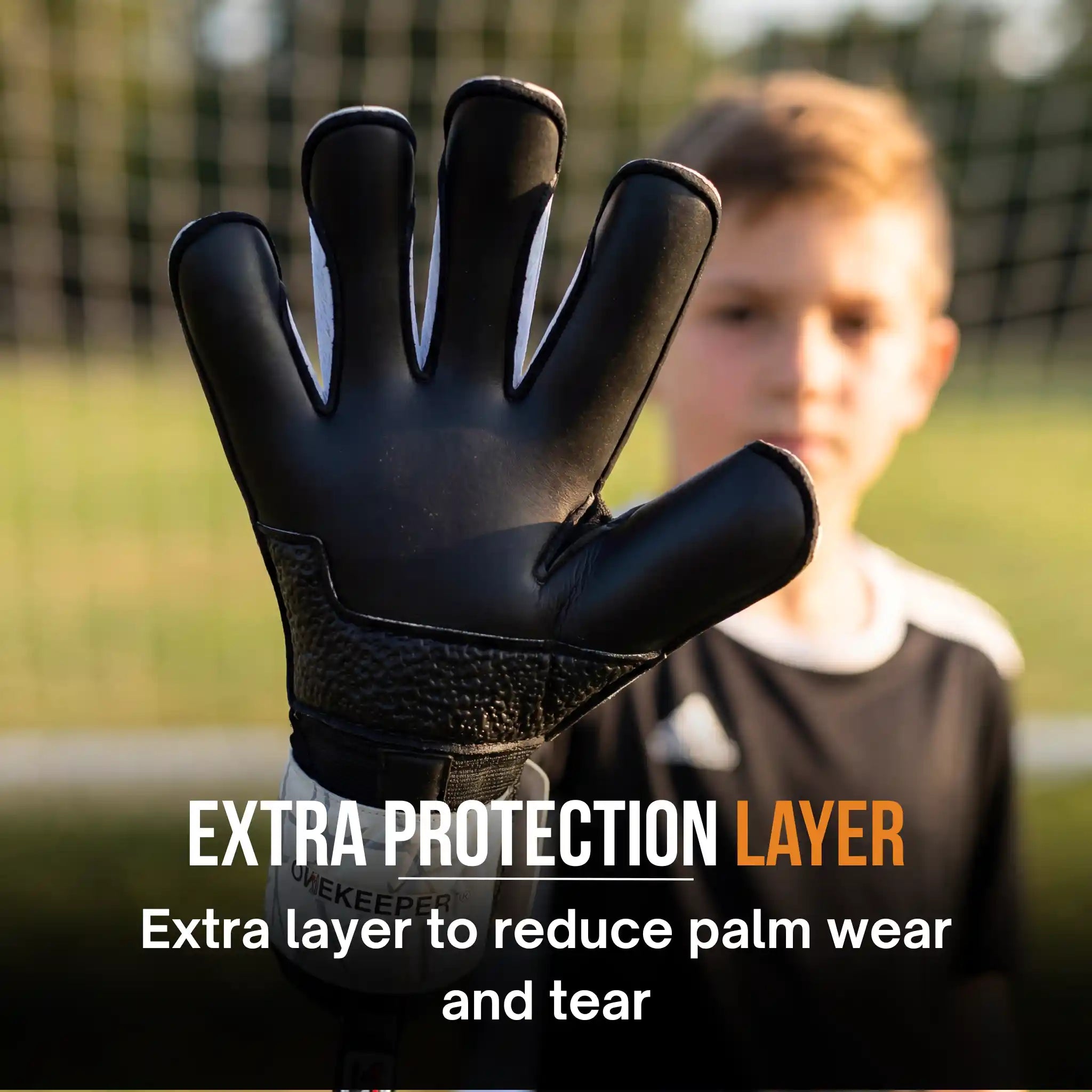 onekeeper vector evolution white and Black goalkeeper glove with text about extra protection layer on a blurred background of a person on a soccer field.