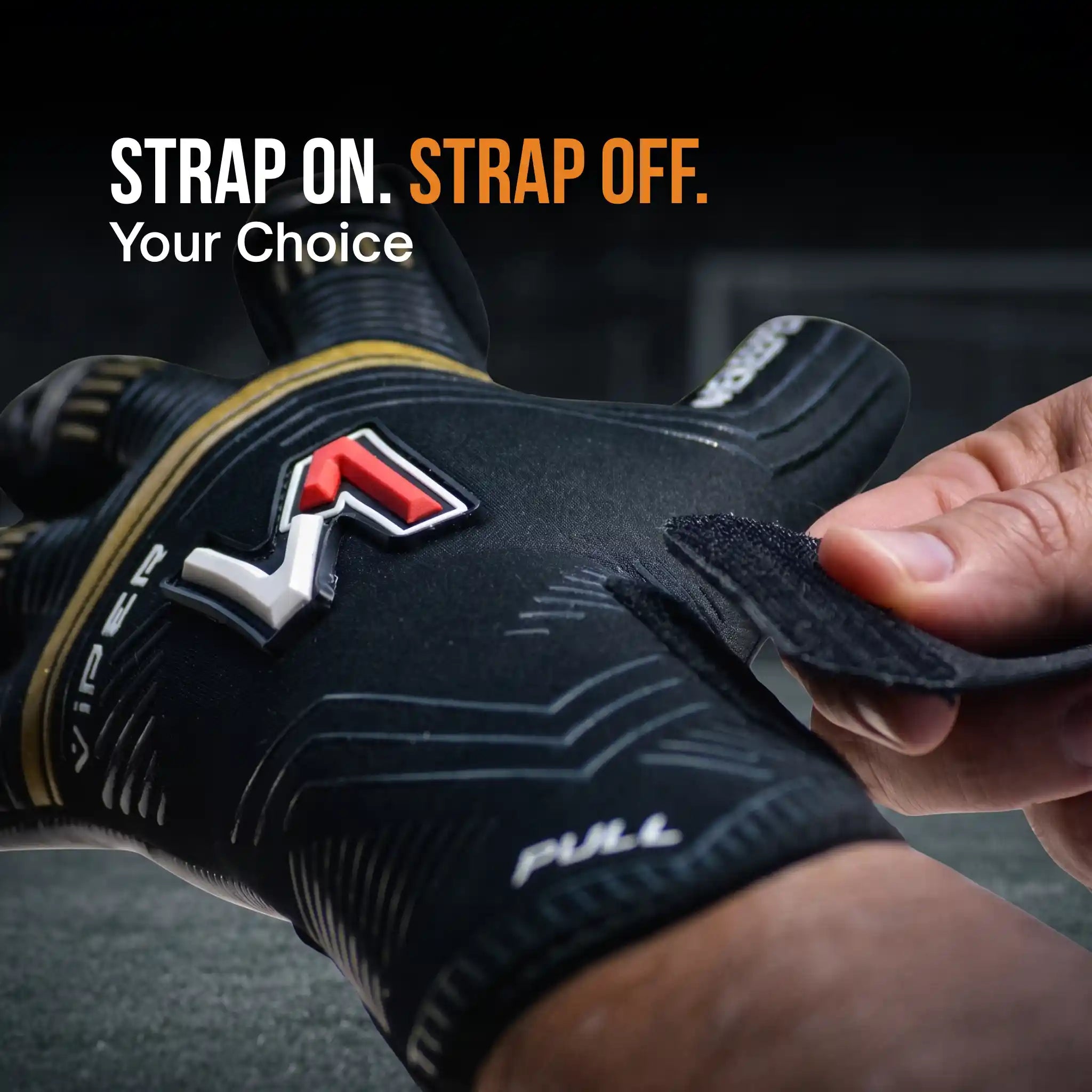 A close-up of a onekeper viper black and gold glove being worn on a hand, with a Velcro strap being fastened. The glove features a prominent red, white, and black logo on the back of the hand, and the text 'STRAP ON.
