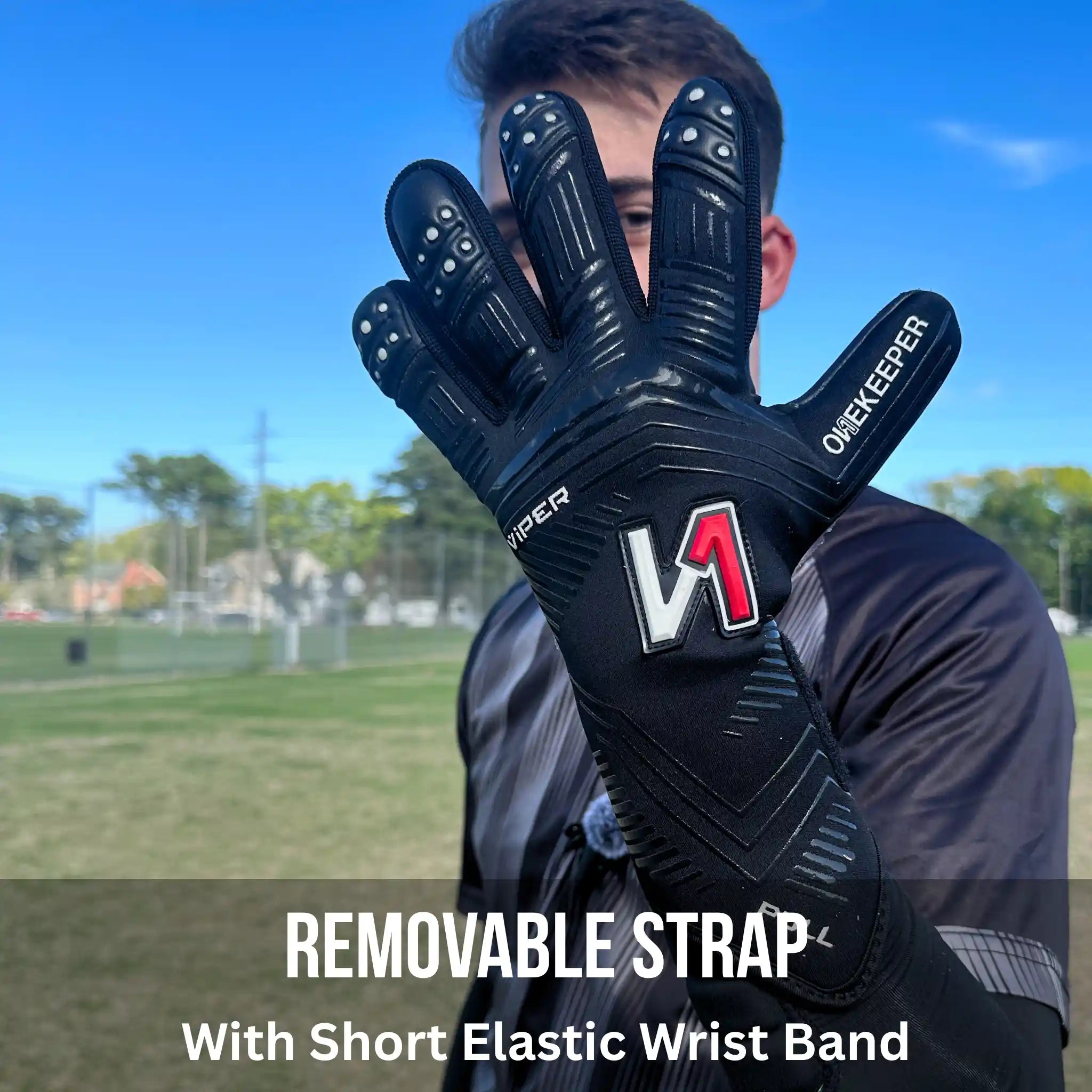 Person holding a onekeeper viper black glove with a visible brand logo on a sports field background