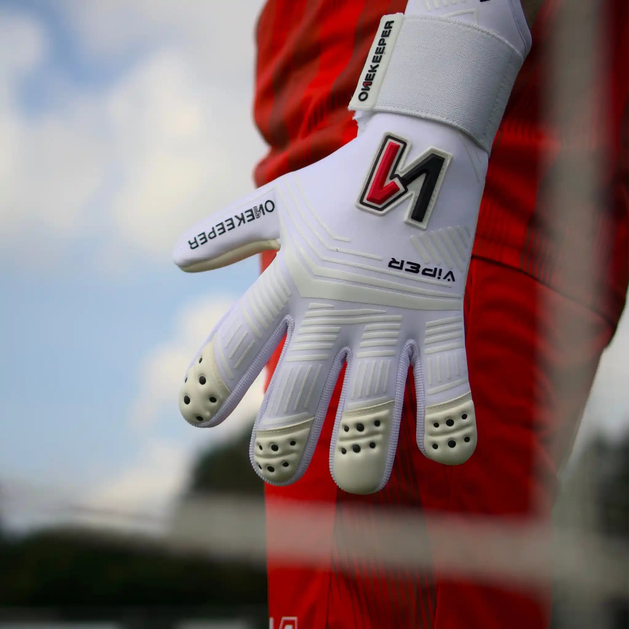 ONEKEEPER Viper White goalkeeper glove with black text and red logo against a blurred background