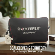 Black pouch with 'ONEKEEPER' branding on a surface with books and a glove in the background.