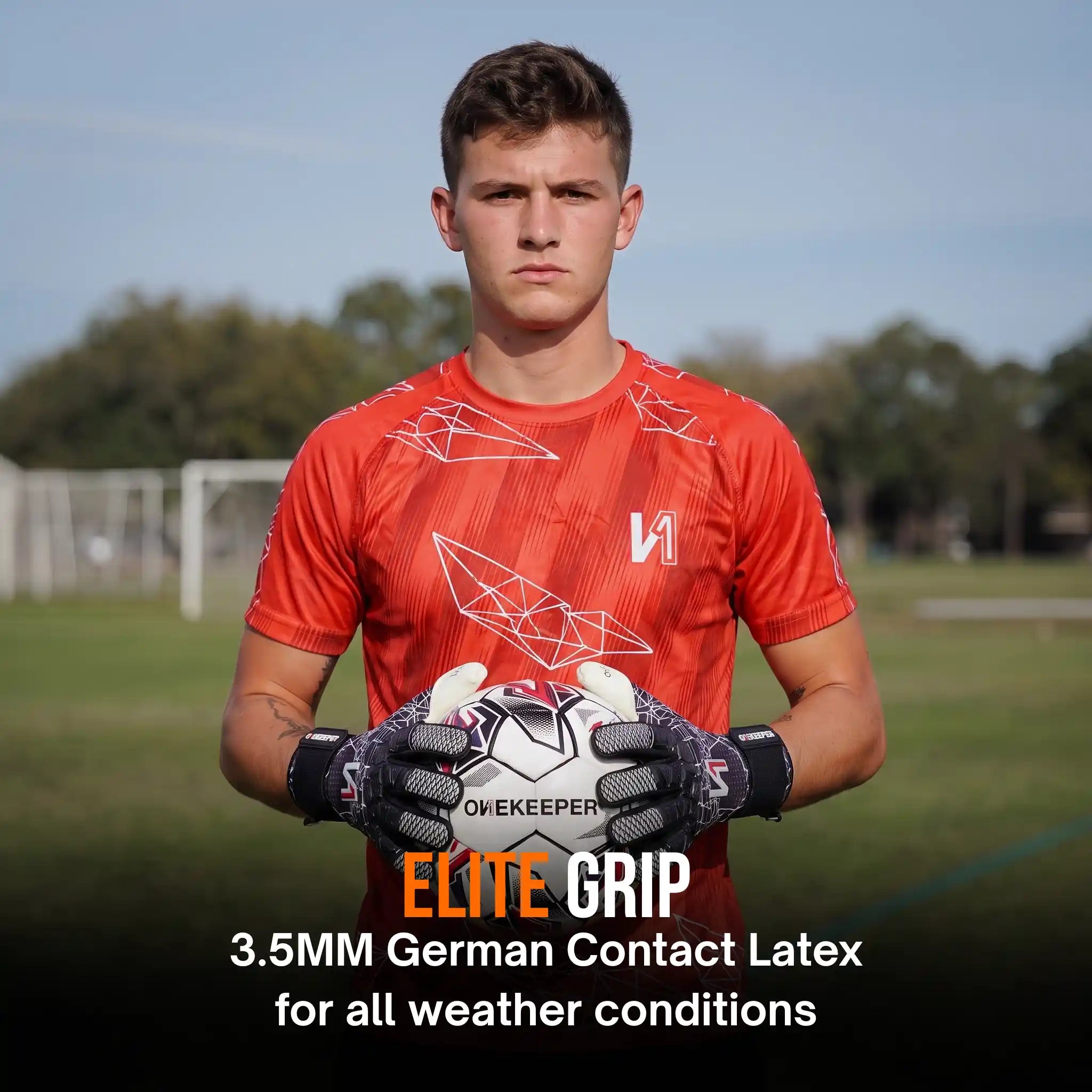 A male goalkeeper stands on a grassy field holding a white soccer ball, wearing an orange-red athletic jersey with a onekeeper ctec black goalkeeper gloves. Text at the bottom reads 'ELITE GRIP 3.