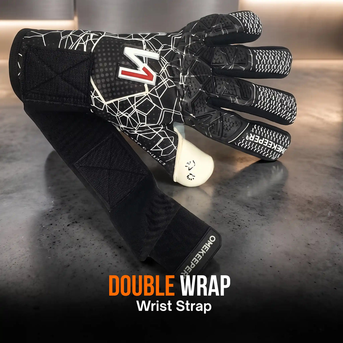 A  onekeeper ctec black goalkeeper glove with a black and white geometric web pattern and a red and white 'M' logo, shown with a black double wrap wrist strap. The text 'DOUBLE WRAP Wrist Strap' is displayed at the bottom.